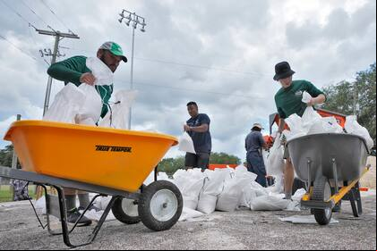 del departamento de parques y jardines de Tampa, Florida, ayuda a los residentes con costales de arena antes de la llegada de la tormenta Idalia, el 28 de agosto de 2023, en Tampa, Florida. (AP Foto/Chris O'Meara)
