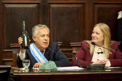 Cornejo levanta una botella de vino, junto a una roca con cobre, para asegurar que la minería y la vitivinicultura pueden convivir en Mendoza.
