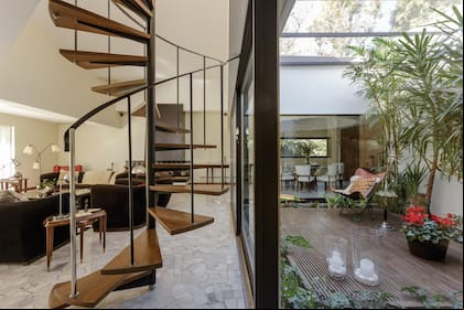 En el living se reconstruyó el piso monolítico de escallas de mármol y en el jardín de invierno se hizo el deck igual al existente pero con varillas de madera más finas y terminación es plastificada. Silla 'BKF' y mesa de fumador de los años '50, compradas en una compra-venta en Uruguay.