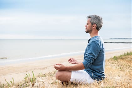 He is meditating with his hands turn up to the sky.