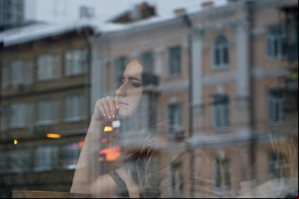 Mujer joven mira a través de una ventana.