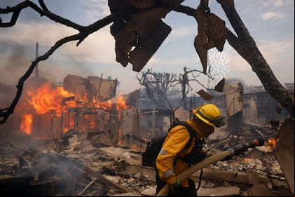 Un bombero combate un incendio alrededor de una estructura calcinada en el vecindario de Pacific Palisades, en Los Ángeles, California, el miércoles 8 de enero de 2025 (AP Foto/Etienne Laurent)