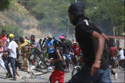 Un grupo de personas huye de los gases lacrimógenos disparados por la policía para dispersar a los manifestantes que exigían a la policía y al primer ministro medidas inmediatas contra las pandillas en Puerto Príncipe, Haití, el lunes 19 de agosto de 2024. (Foto AP/Odelyn Joseph)