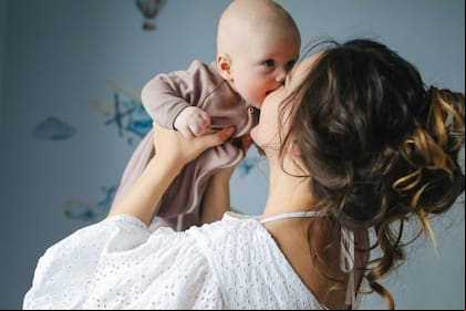 Una madre besa a su bebé recién nacido, un gesto que simboliza el amor infinito y la devoción que comienzan desde el primer instante de vida