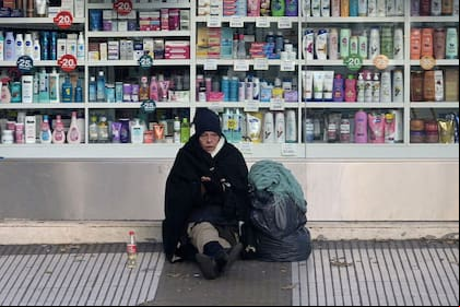 Una mujer pide dinero en el exterior de una farmacia de la ciudad de Buenos Aires