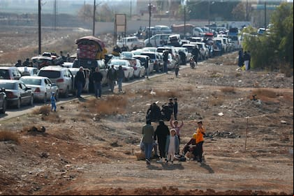 Varias familias libanesas se sientan en medio del tráfico mientras vuelven a Líbano a través del cruce fronterizo de Jousieh, en Siria, el jueves 28 de noviembre de 2024, tras el alto al fuego entre Israel y Hezbollah, que entró en vigor el miércoles. (AP Foto/Omar Sanadiki)
